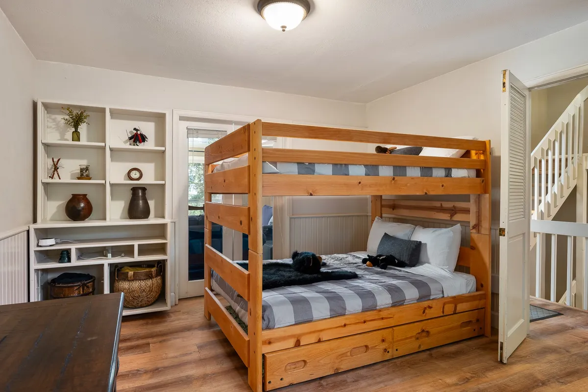 A family-friendly bunk room featuring a bunk bed, shelving unit, and decorative items. The room is playful yet cozy, providing a perfect sanctuary for kids or multi-generational families to enjoy bedtime stories and playful mornings.